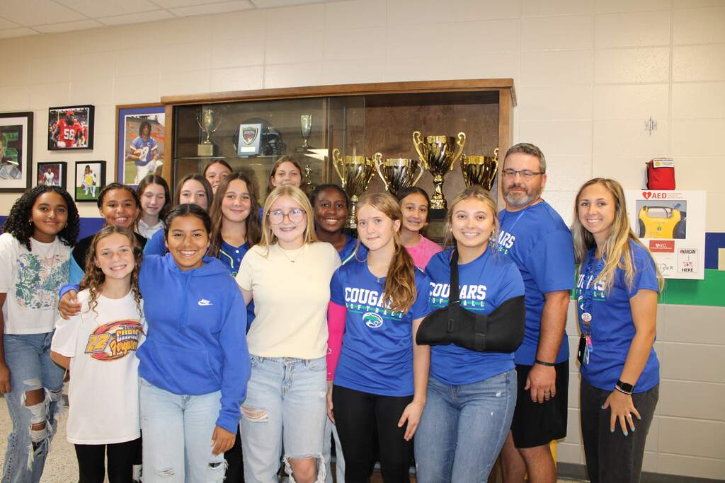 Softball team placing trophy in case