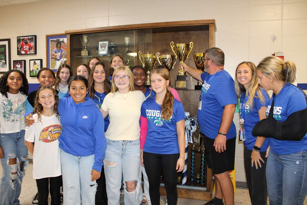 Softball team placing trophy in case