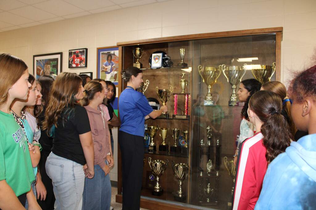 Vollyball team placing trophy in case