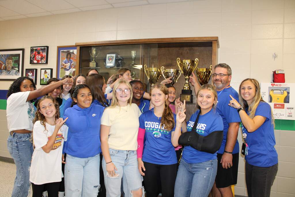 Softball team placing trophy in case