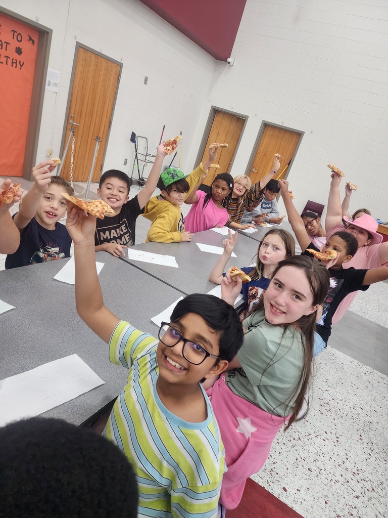 A group of 4th grade students enjoying pizza in the school cafeteria.
