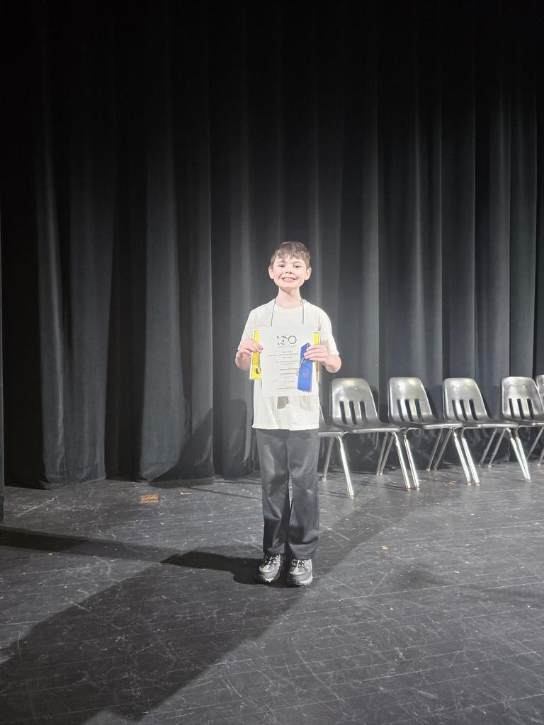 First place spelling bee winner holding his certificate and ribbon
