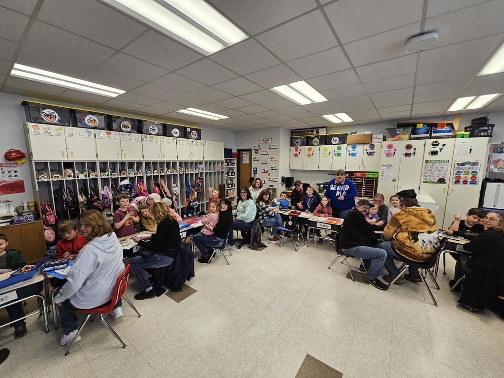 Kindergarten classroom picture with grandparents and thier grandkids sitting together at desks.