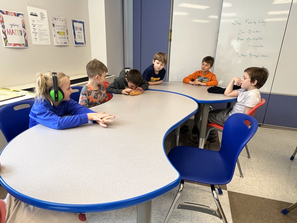 Students sitting a larger table looking at student making pie filling