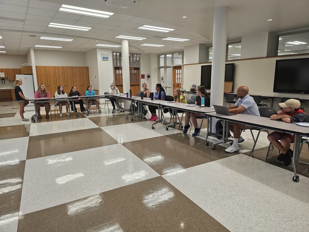 Student council members sitting at tables in a L shape
