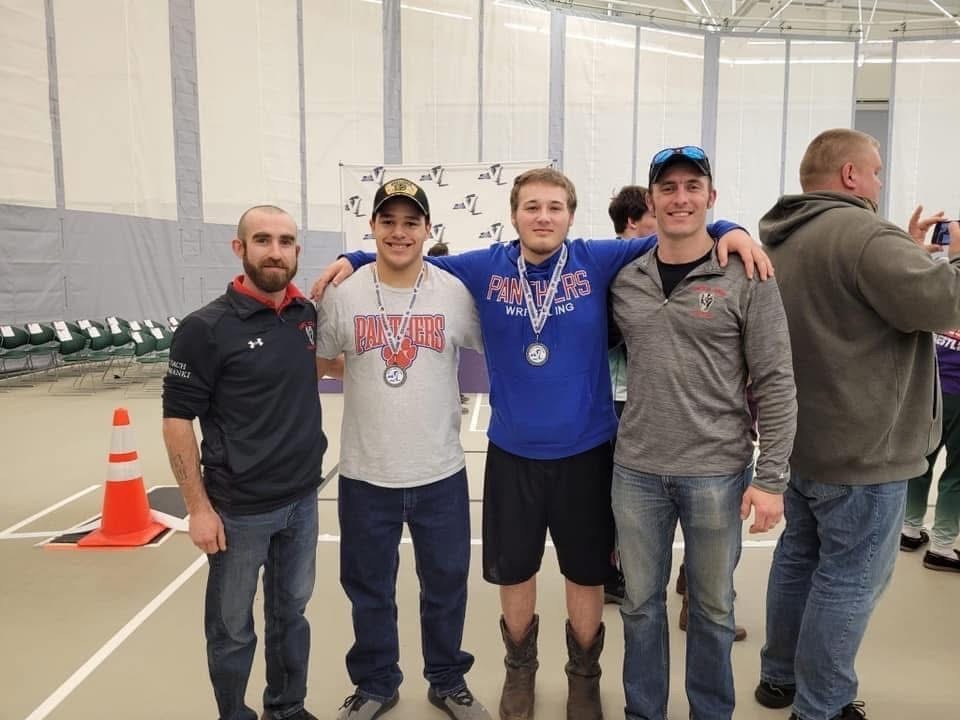 Group shot of 2 coaches with 2 wrestlers wearing medals