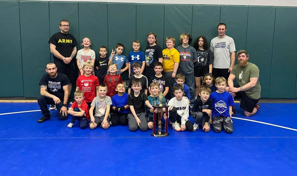 Group picture of youth wrestling with a trophy