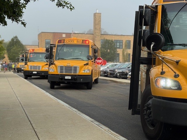 Busses parked facing camera with stop signs out.