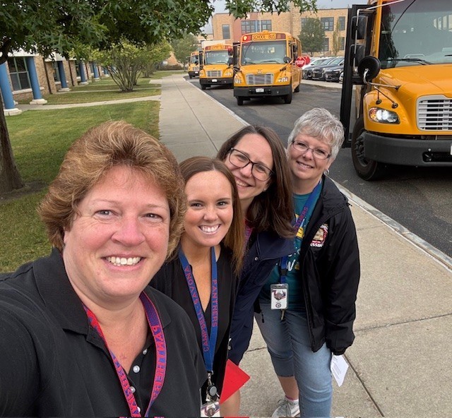 Picture of 4 adults posing for camera in front of busses