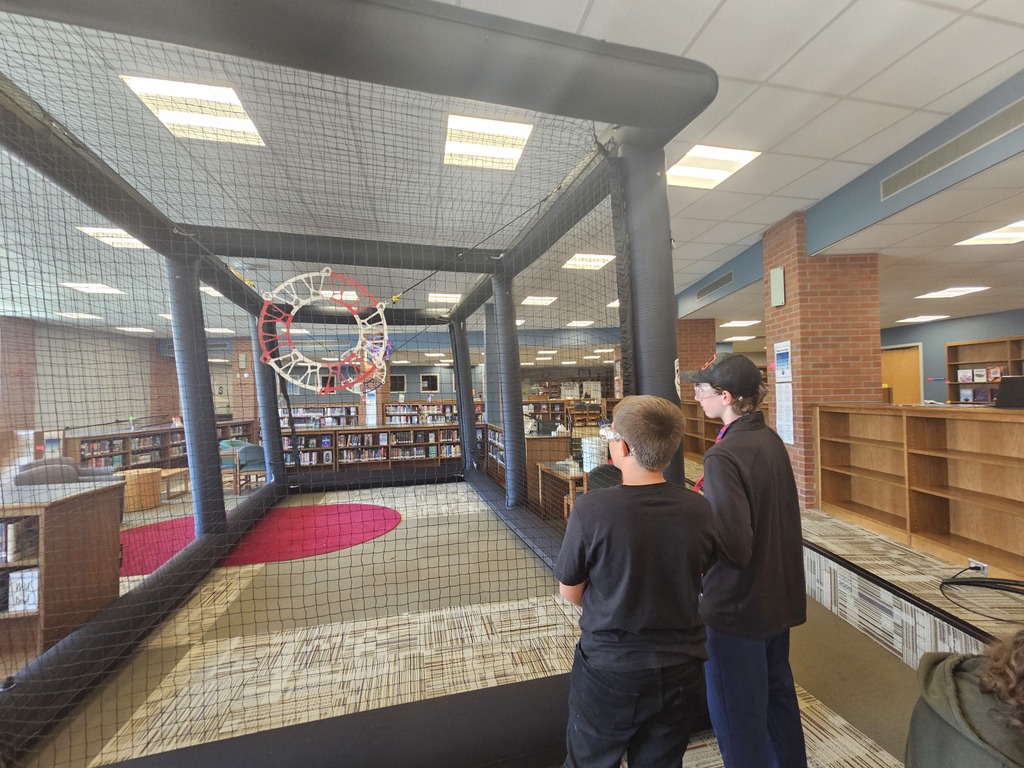 2 students  flying drones in the cage.