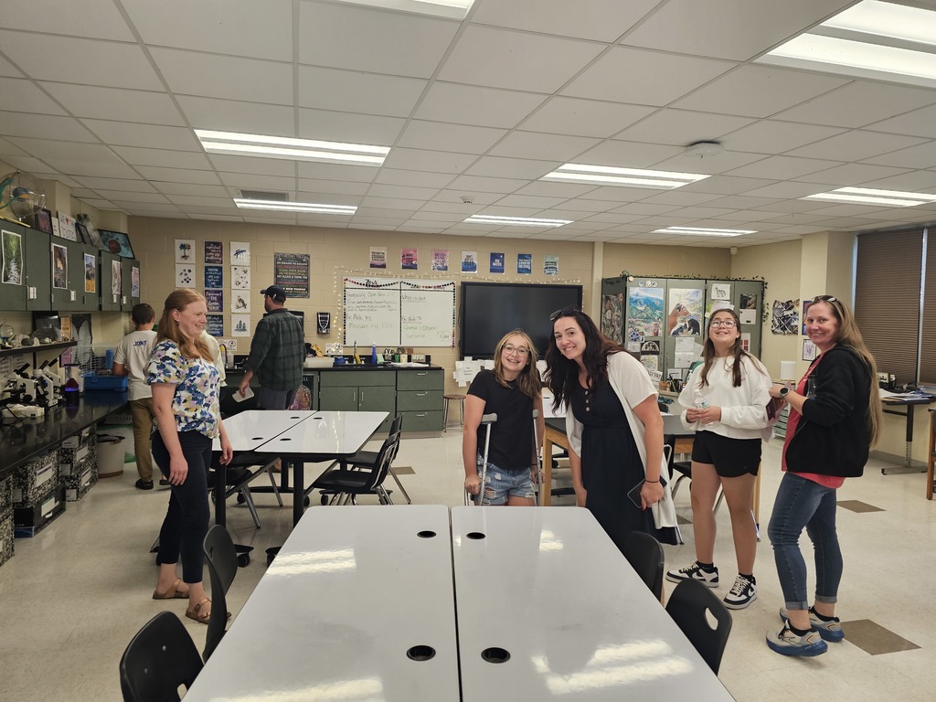 Students in classroom at open house with parents and teacher smiling