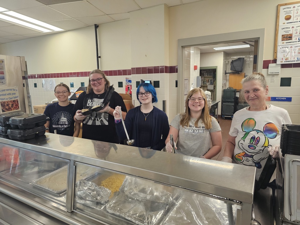 Drama club students serving chicken dinner in cafeteria