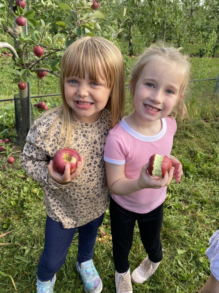 Two students smiling holding and eating apples