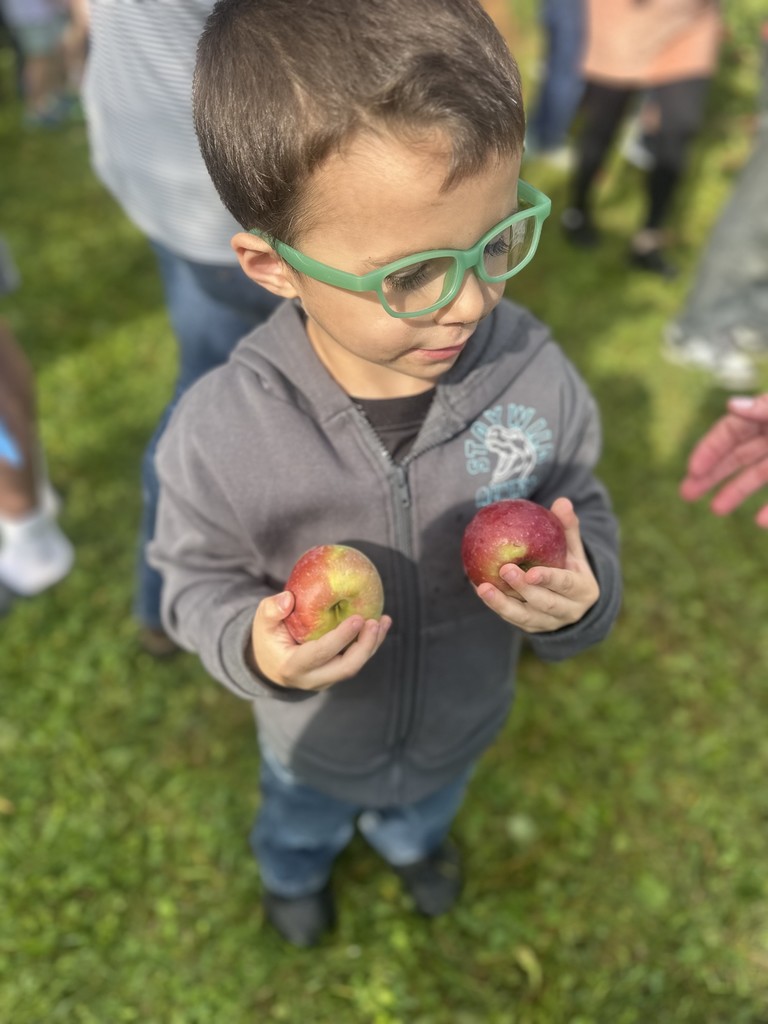 Student with glasses holding two apples.