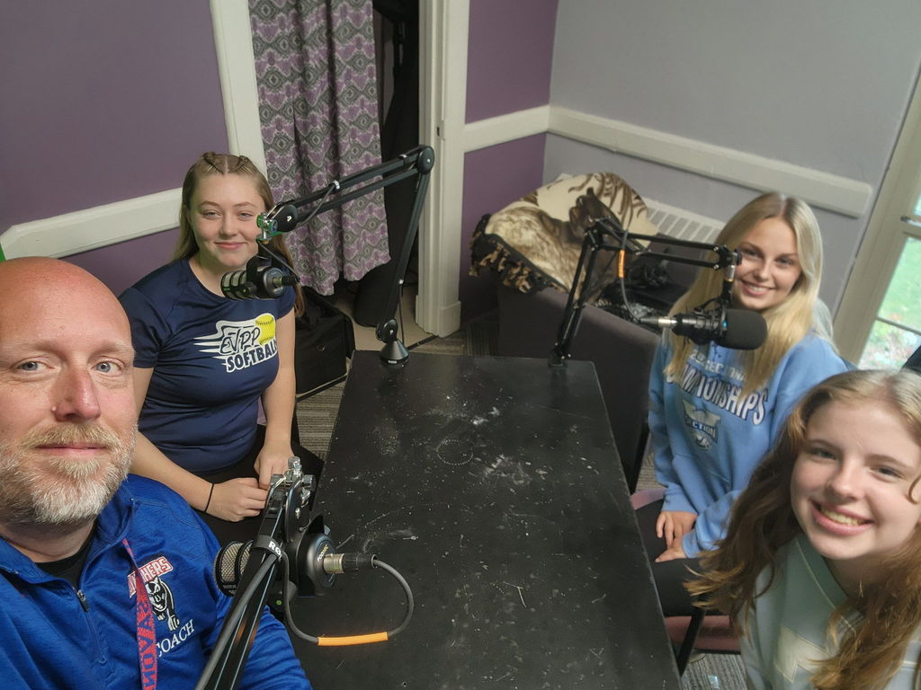 students sitting at table doing a podcast