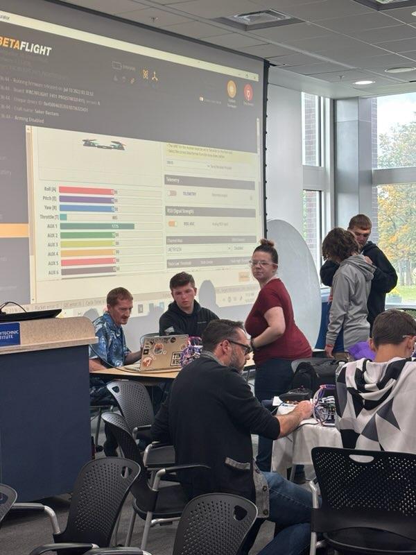 Student working at tables with adults on computers