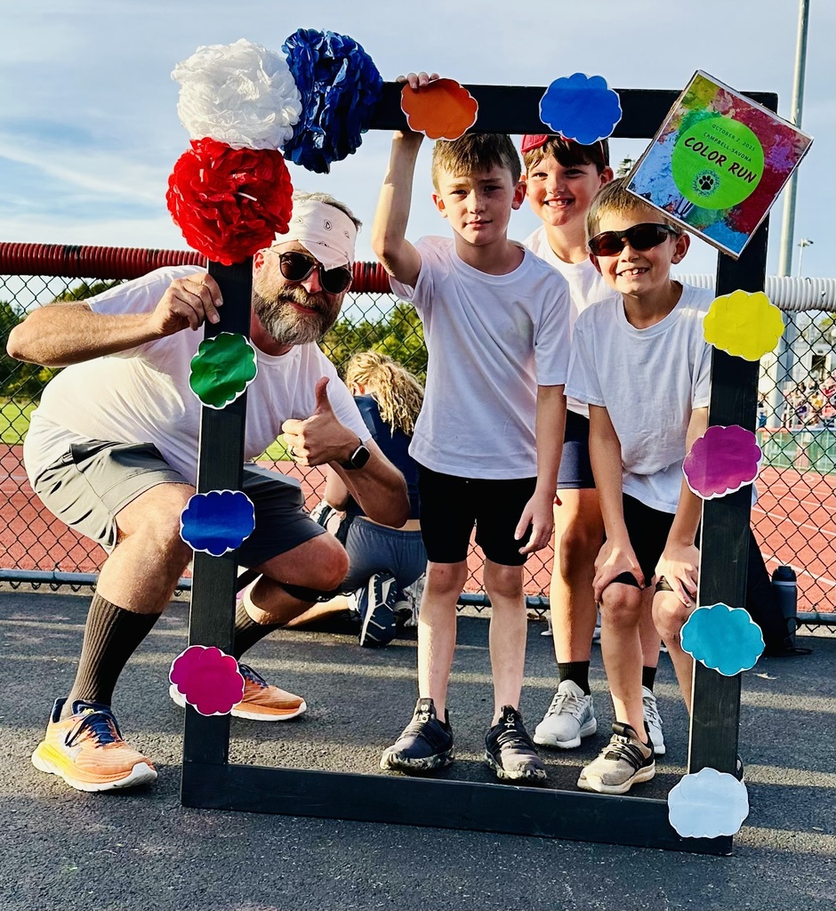 Teacher and student posing in front of a frame in white shirts for the color run.