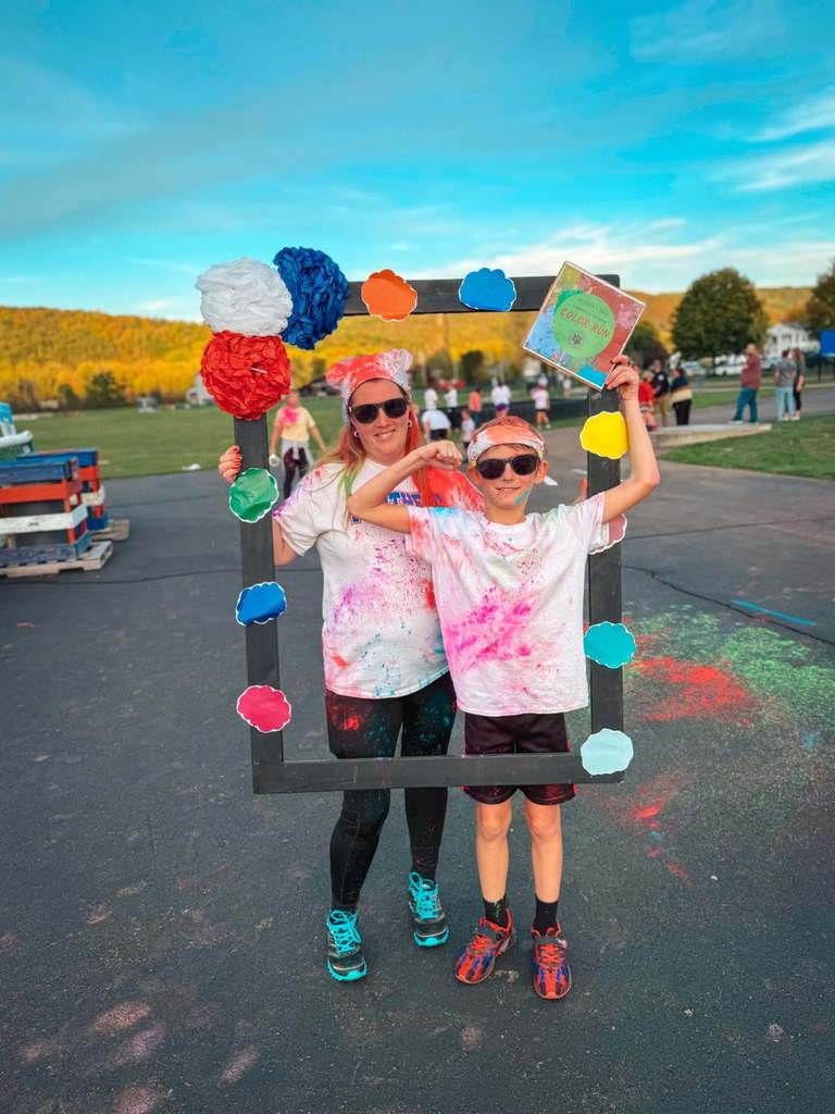 Student and parent posing in a frame after color run with smiles