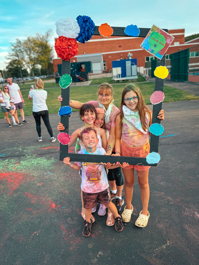 Students posing in a frame after color run with smiles