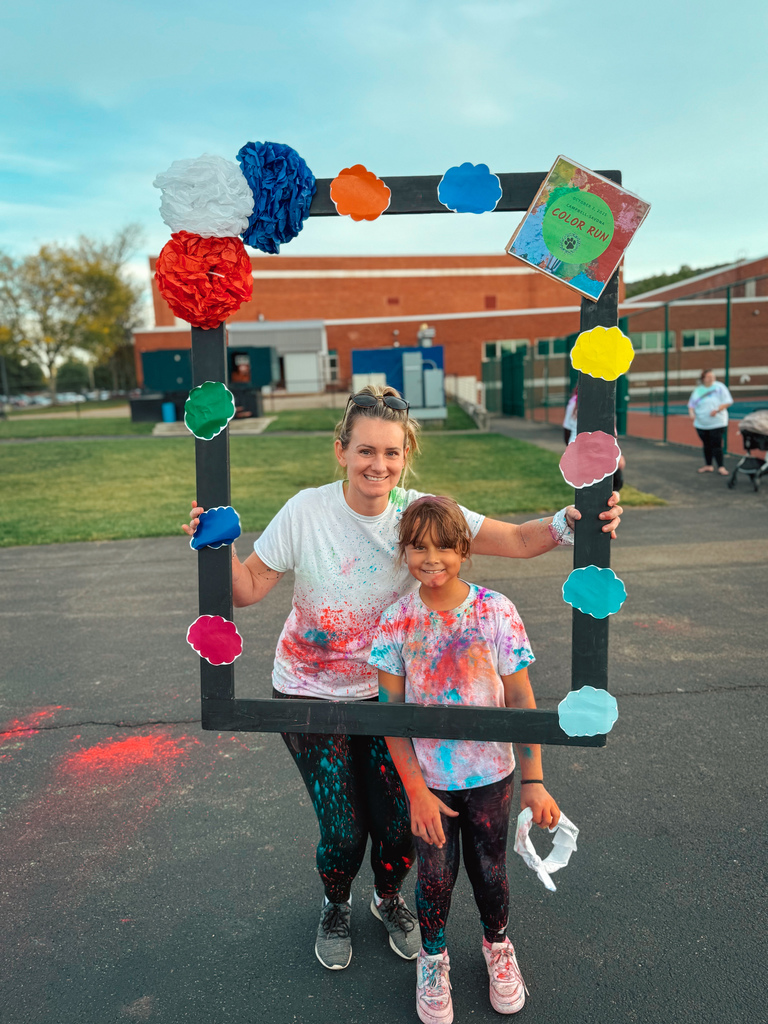Student and parent posing in a frame after color run with smiles