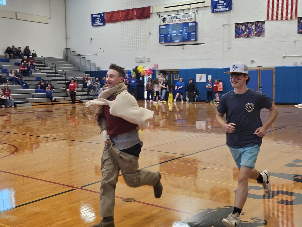 Two students running playing game at pep assembly