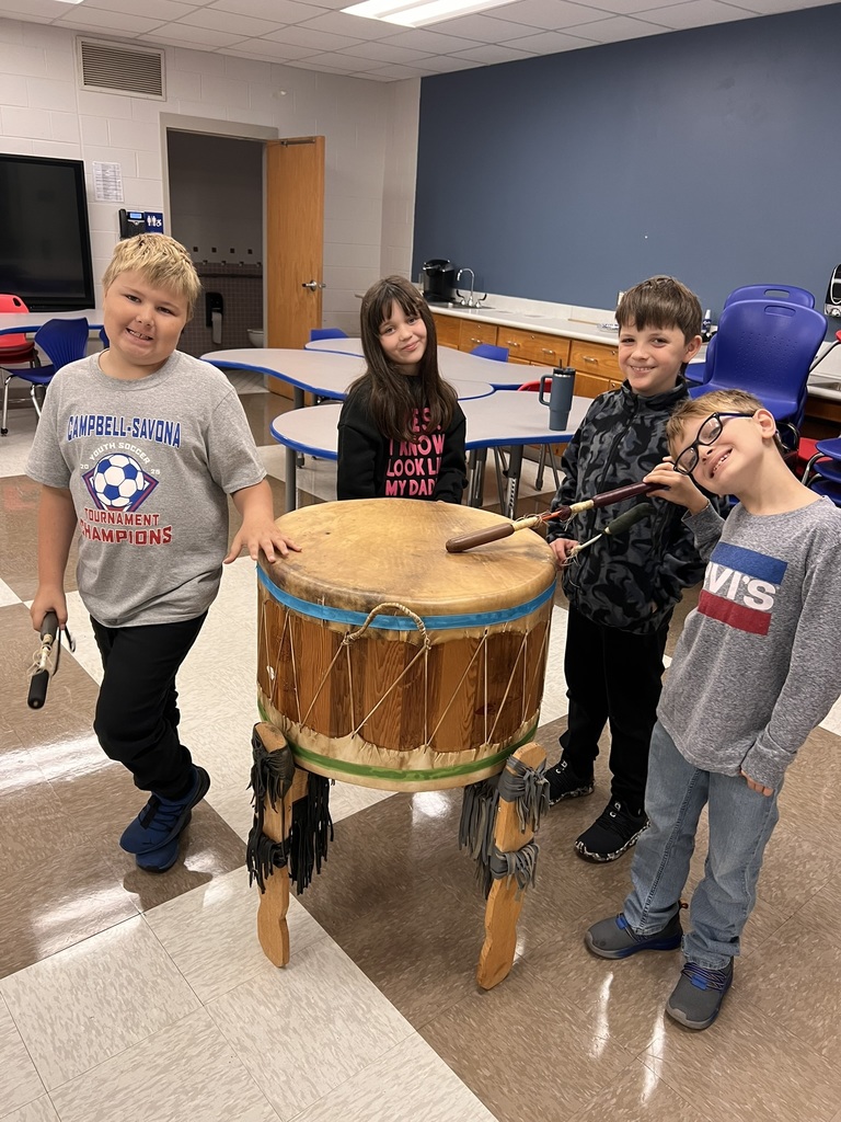 Students gathering around big native american drum smiling for camera