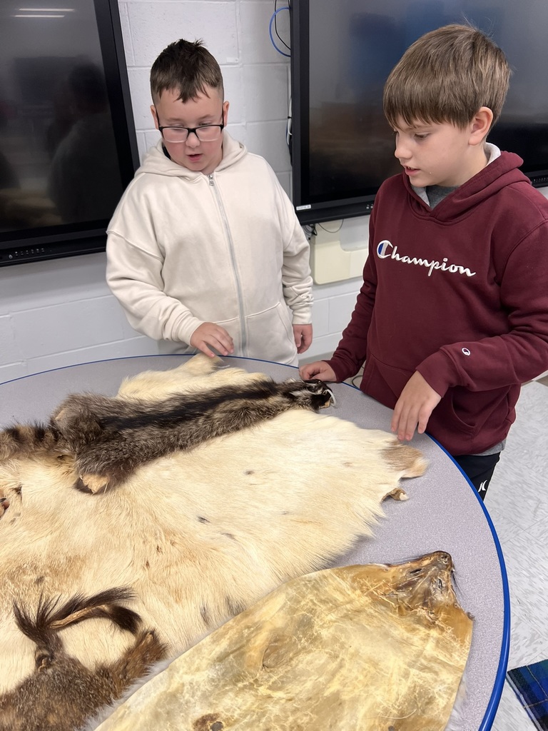 2 students standing at table looking at furs