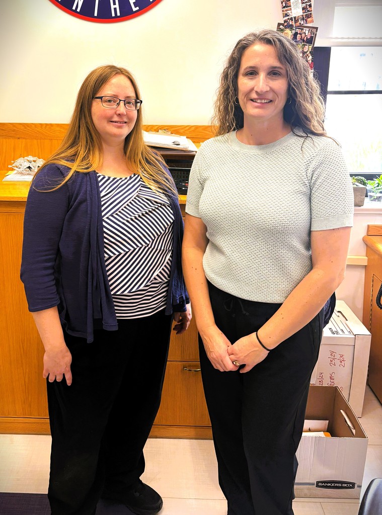 Kim and Cassie posing for picture in office both wearing black pants.