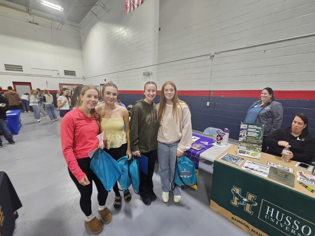 4 students standing together smiling for picture at college info booth