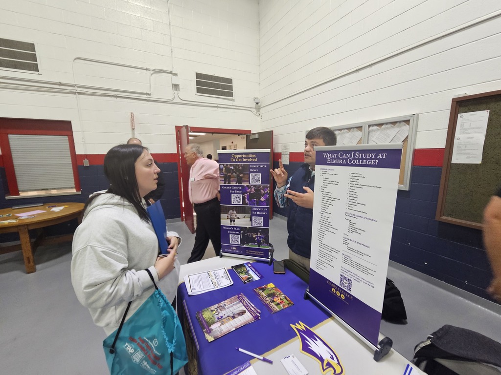 Student with black looking at Elmira college information at college fair