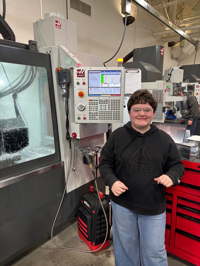 Student in black sweatshirt and safety glasses smiling for picture