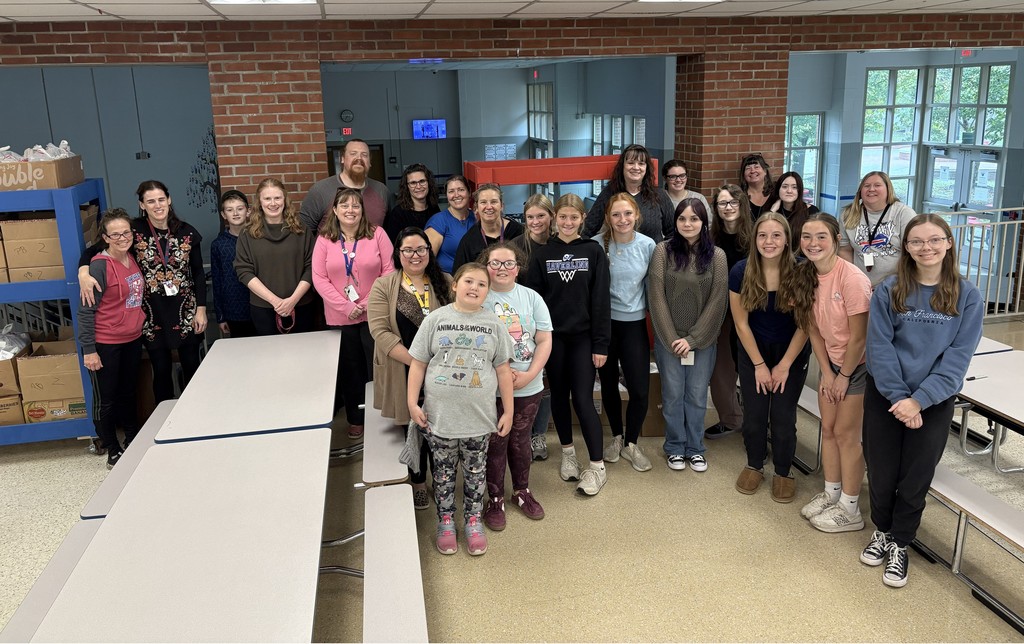 Group photo in cafeteria with students and adults smiling