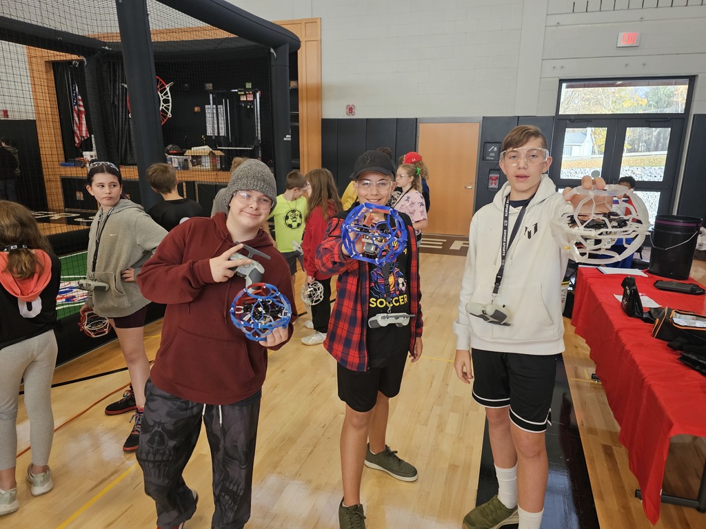 Three students holding drones posing for picture