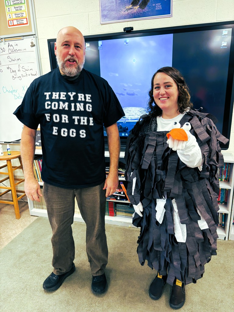 Two teachers pone dressed as a chjicken the other in a black t shirt with lettering