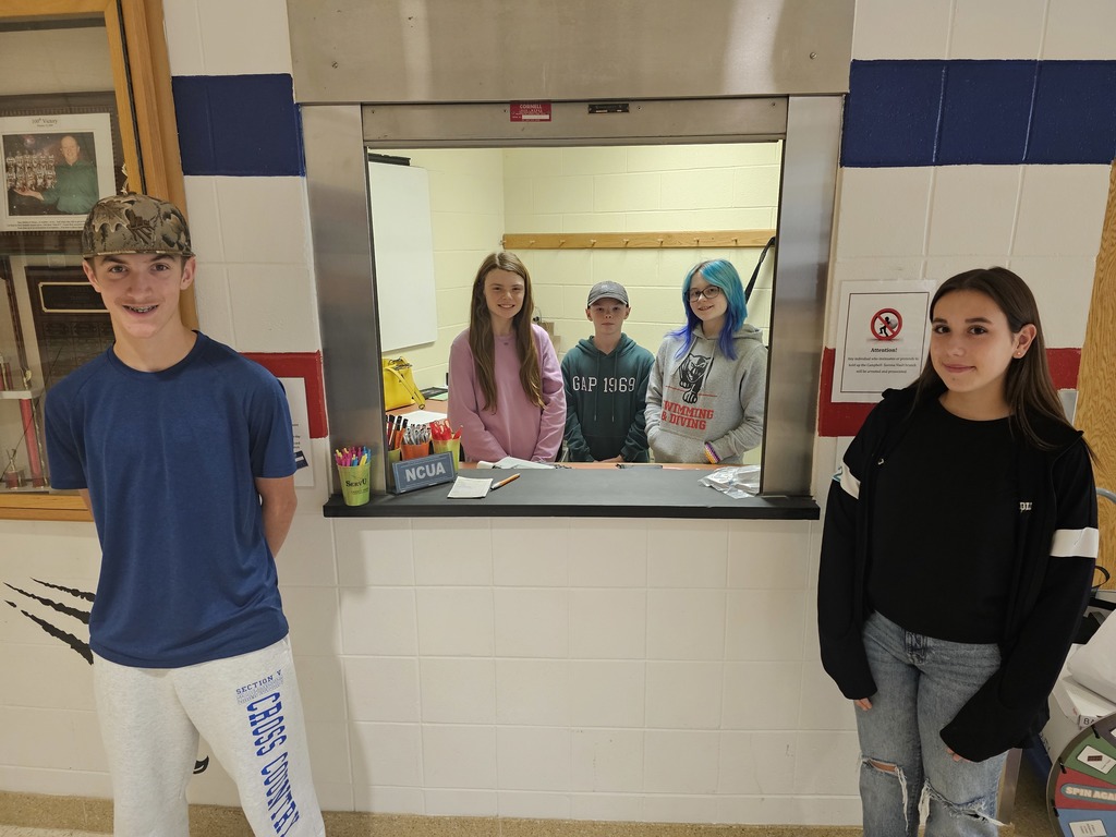 Picture of 5 students posing at the teller station for banking