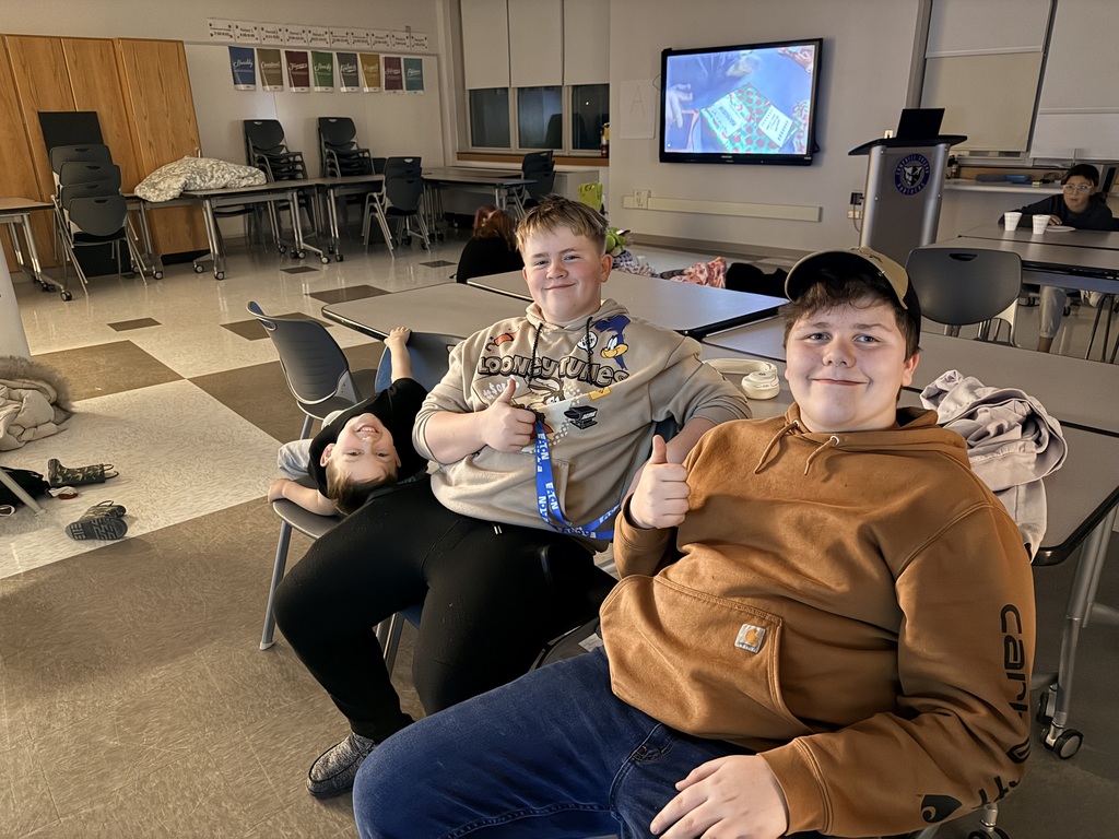 Three students giving a thumbs up sitting in chairs watching the grinch