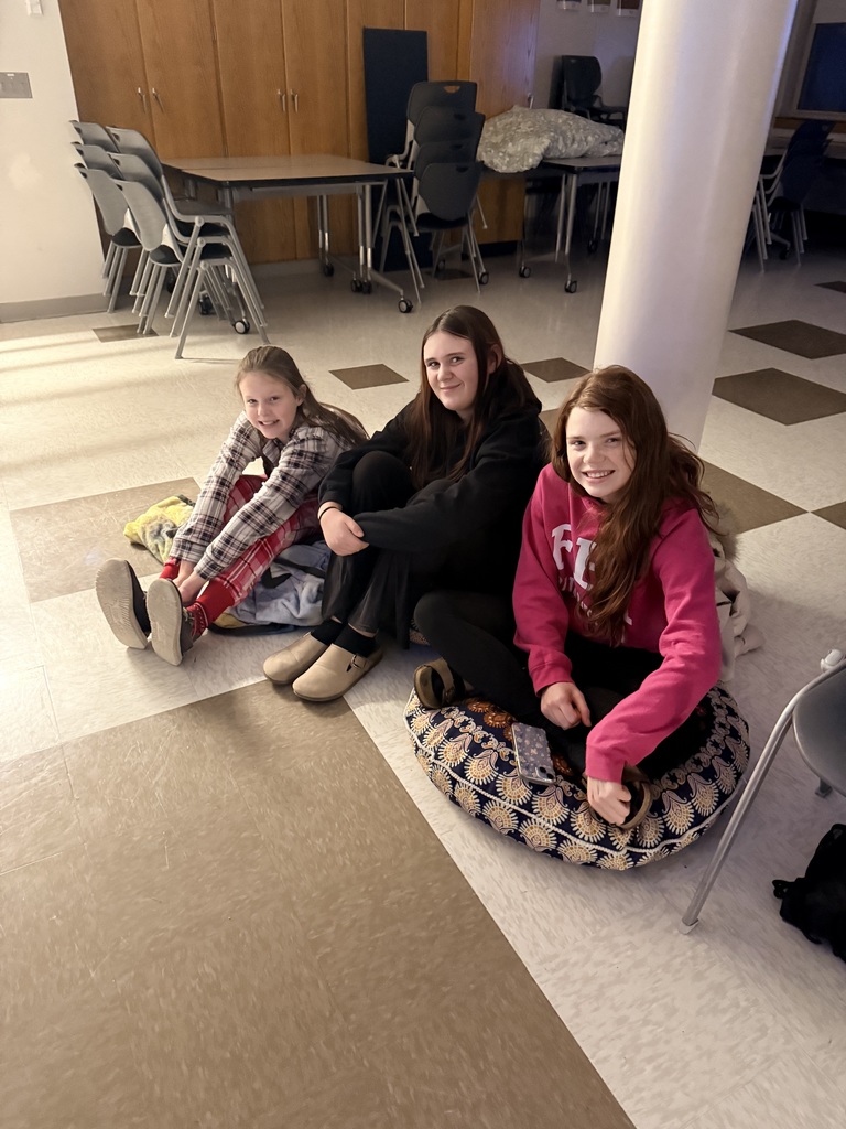 3 students in comfortable clothes sitting on floor smiling