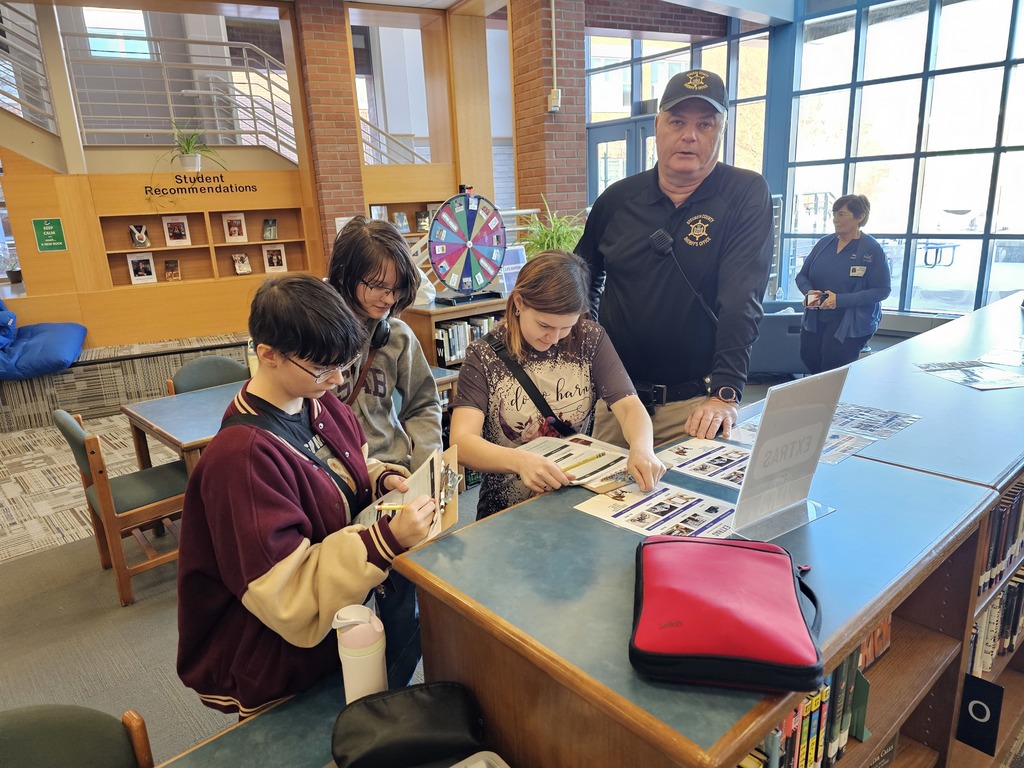 Students standing around SRO looking at items to build a simulation budget.,