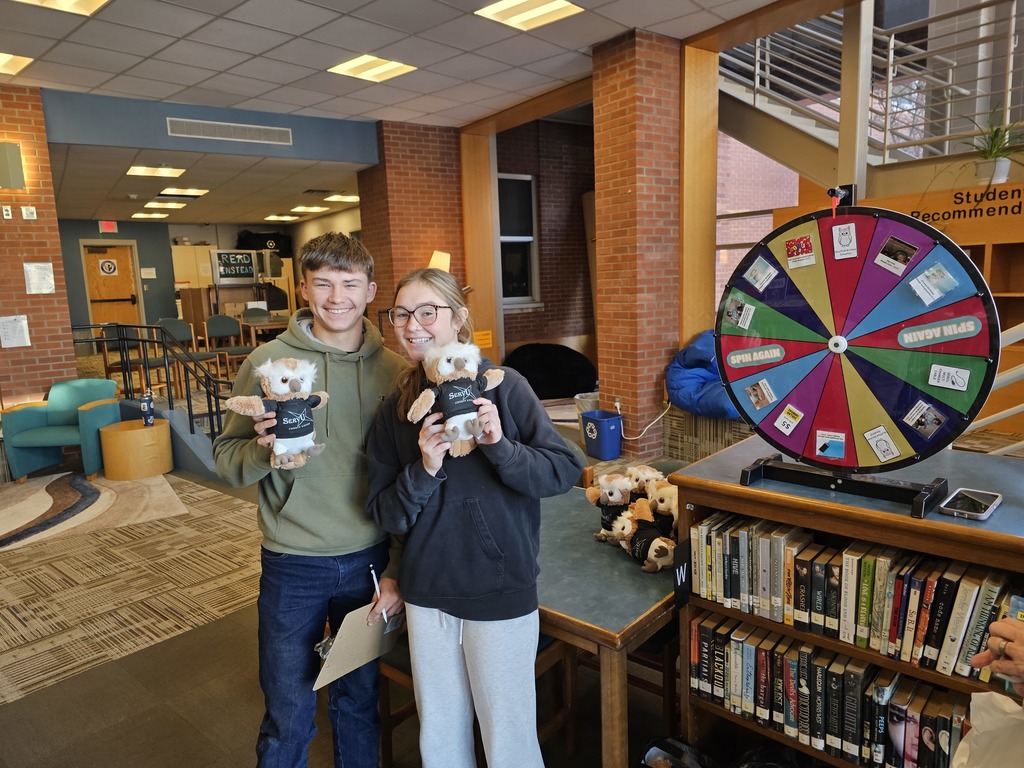 Two students smiling holding owl stuffed animals