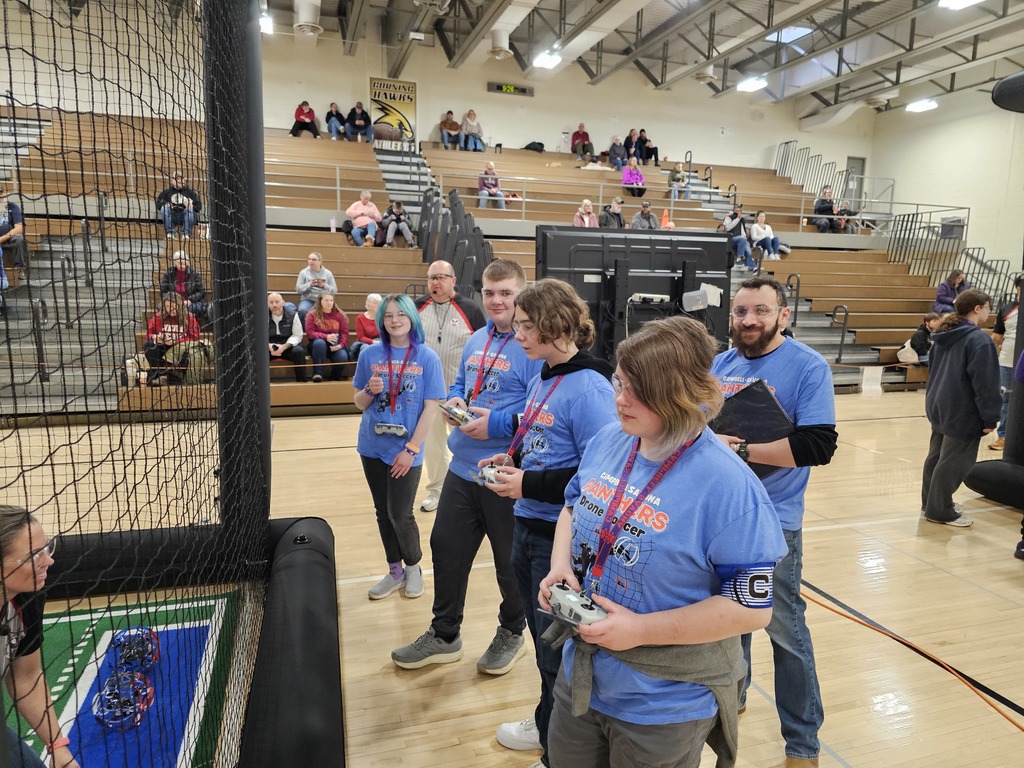 Drone soccer team with controllers and blue shirts with fame faces on for camera