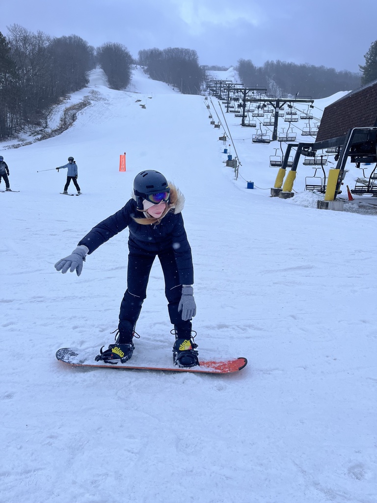 Student standing on his snow board in the snow riding it