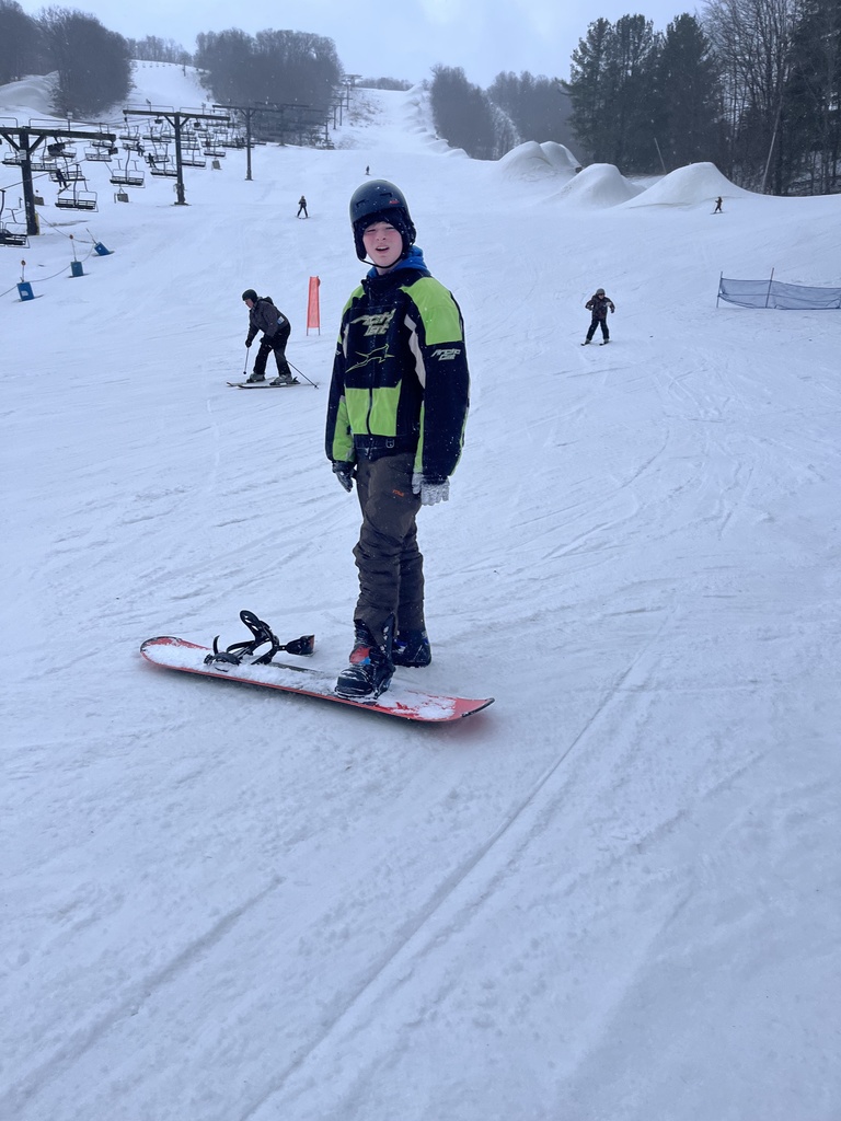 Student standing on his snow board in the snow