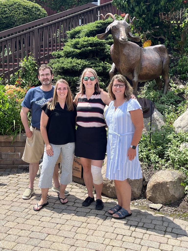Picture of 4 co workers standing in front of rocks and grass