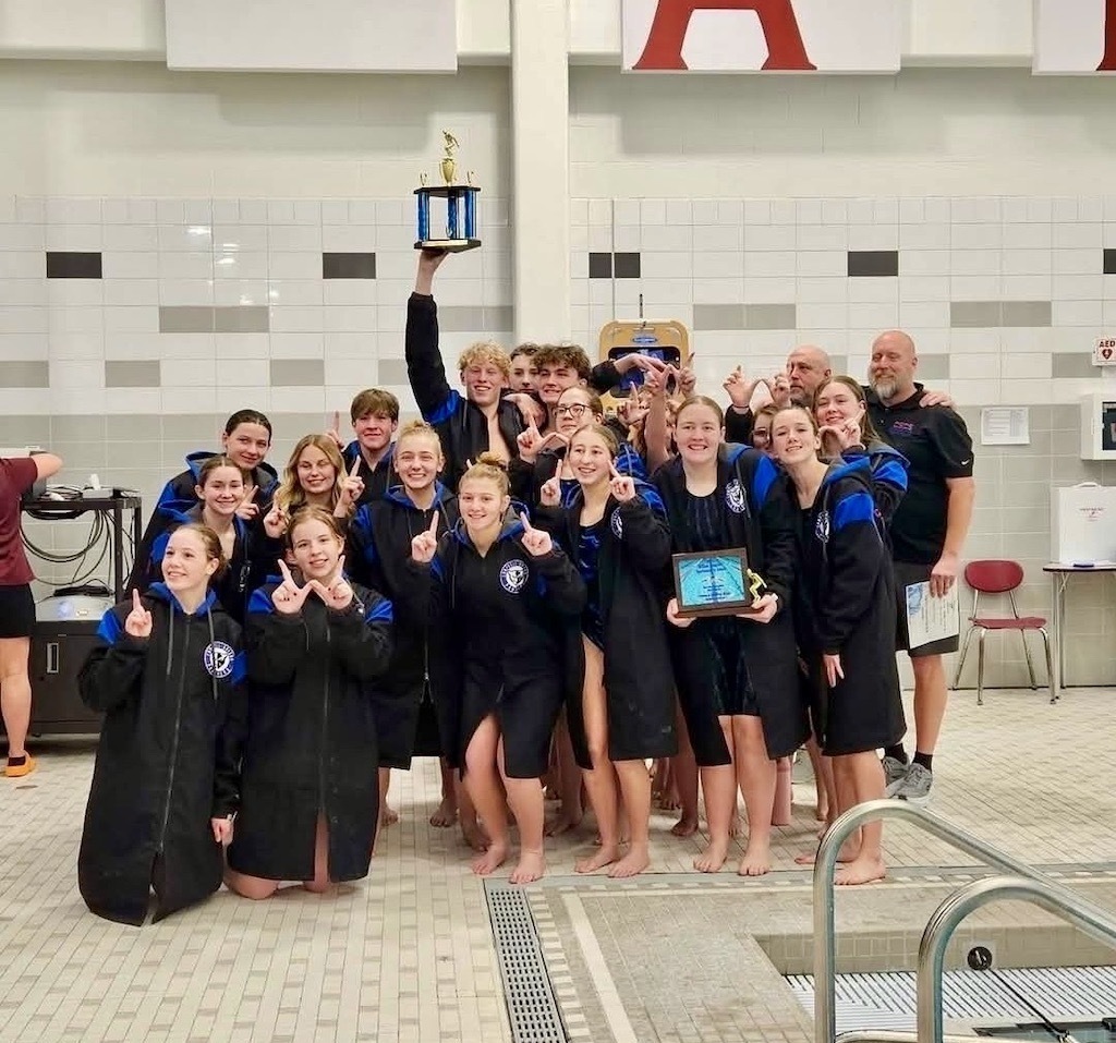 Swim team posing for picture with trophy