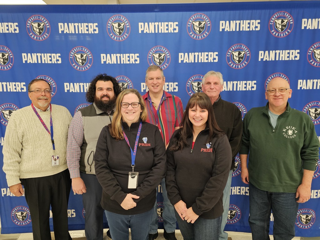 Board of education group photo in front of panther banner
