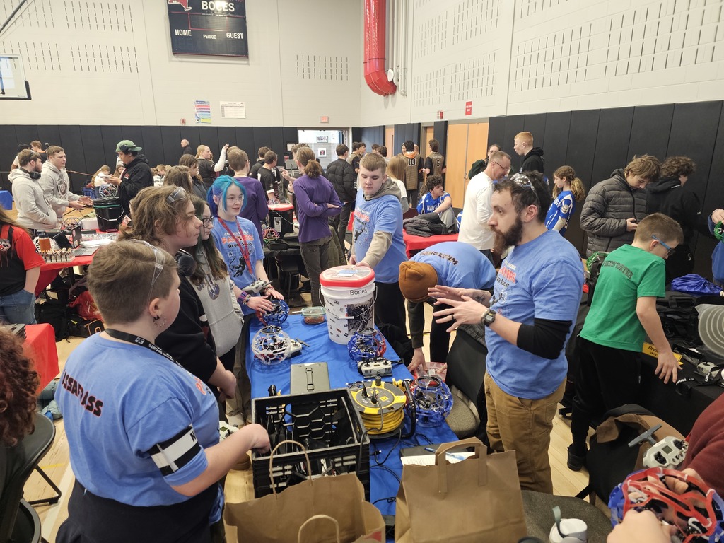 Drone soccer coach talking to team as they work on drones.