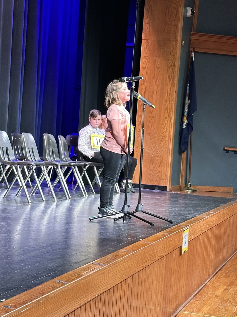 Student standing at microphone at spelling bee on stage