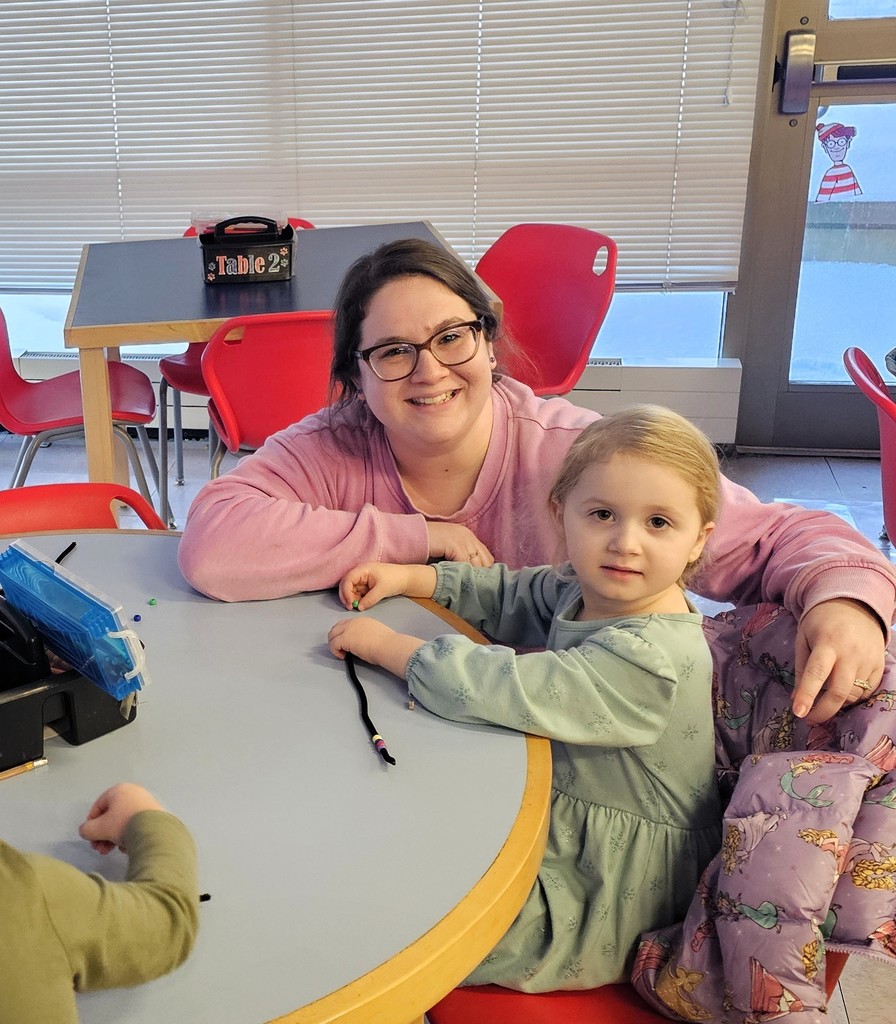 Parent smiling with child sitting at a table