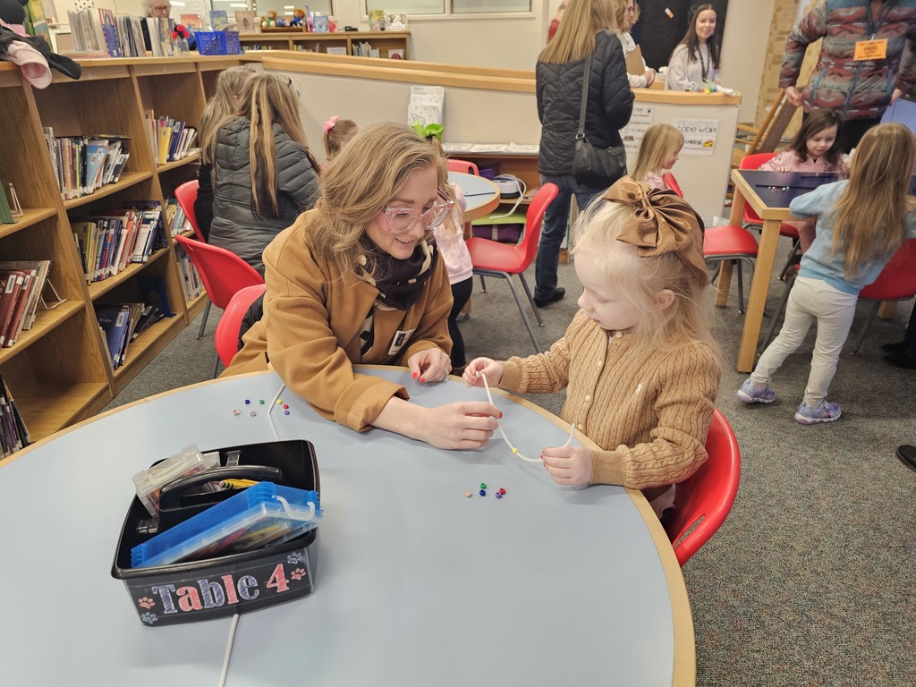 Story hour bracelet making with parent sitting with child and helping