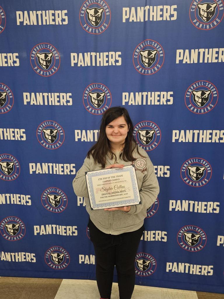 Student standing in front of panther banner holding top of the trades certificate of recognition